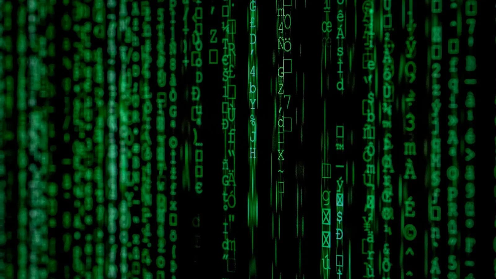 Cascading streams of green code on a dark screen representing automated bot traffic