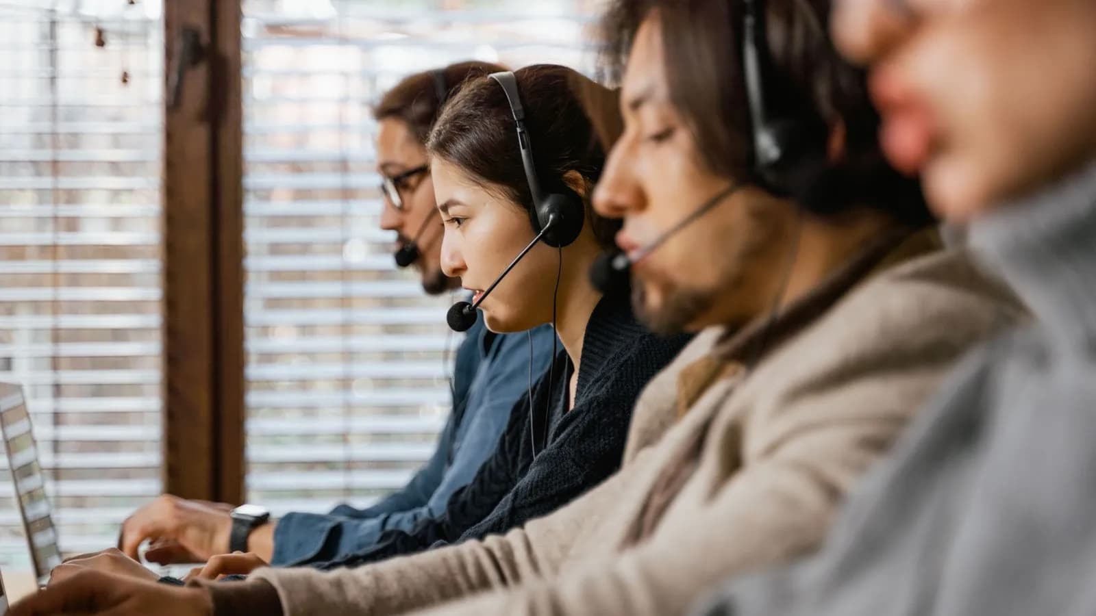 A row of sales reps wearing headsets, grinding through call lists at their desks